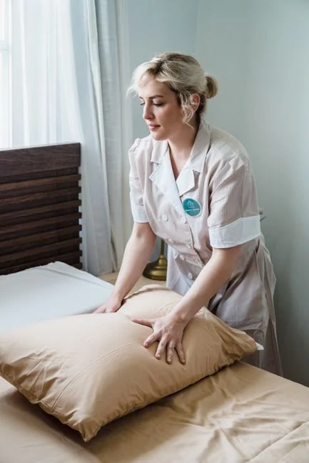 A woman carefully encloses a sofa in protective material while packing boxes in a bright room.